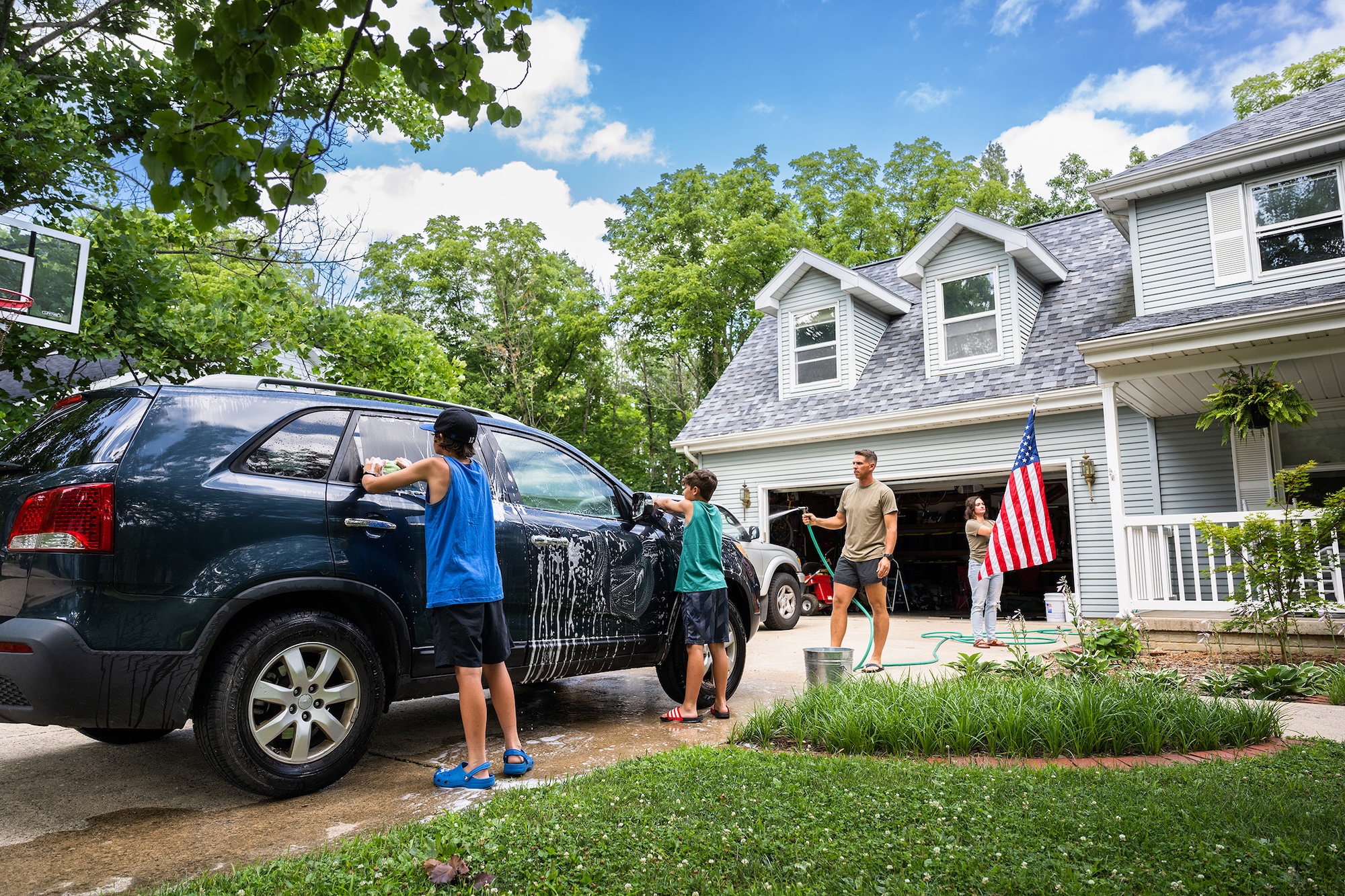 Air force service member washing his SUV with his sons